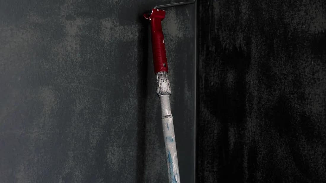 Ferramenta de pintura aplicando acabamento decorativo em parede escura