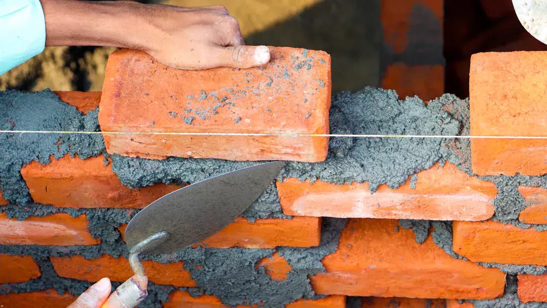 Pedreiro executando fiada de tijolos em alvenaria estrutural